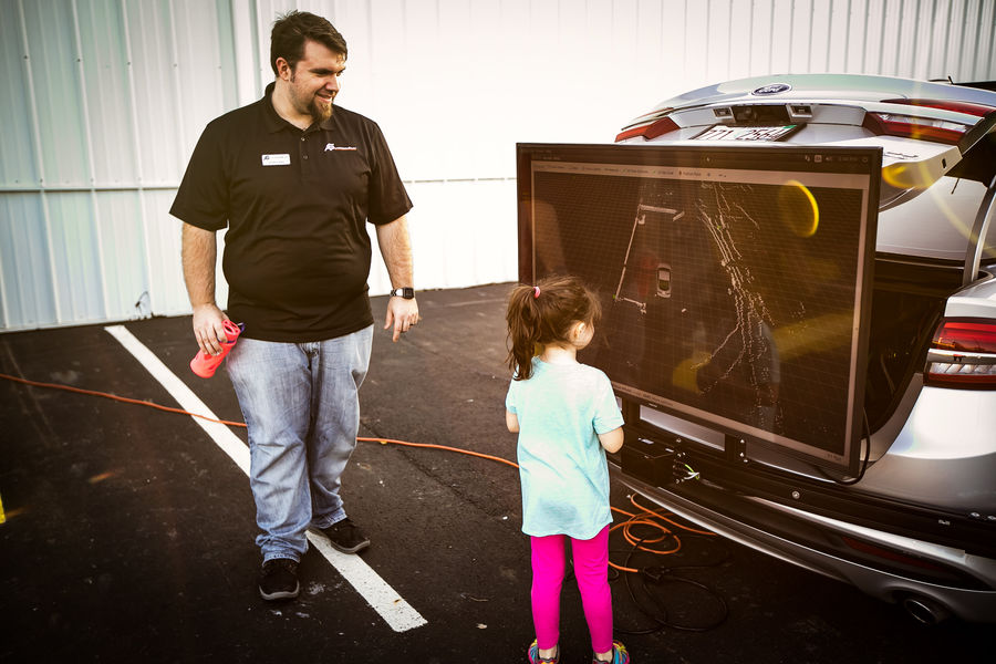 Man and child looking at screen on back of vehicle